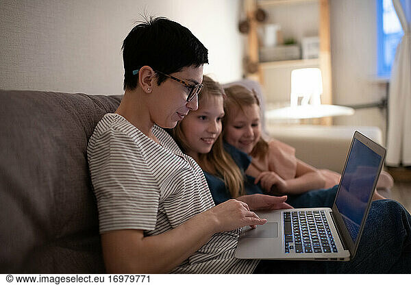 Mother using laptop for work near daughters