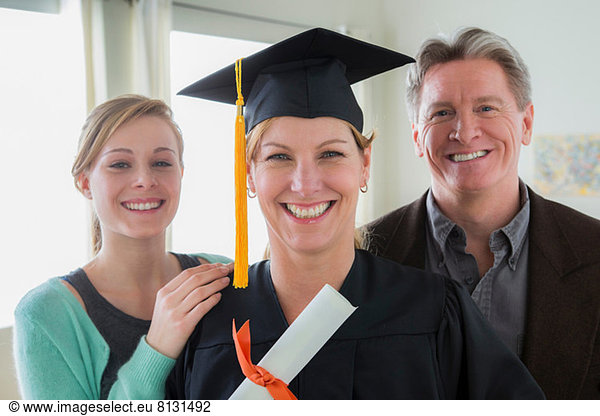 Mother wearing mortarboard with daughter and husband