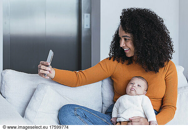 Mother with baby boy taking selfie on smart phone in living room