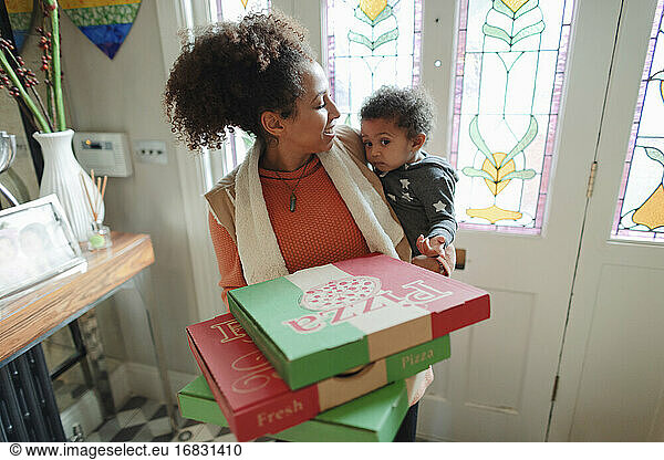 Mother with baby daughter receiving pizza delivery at front door