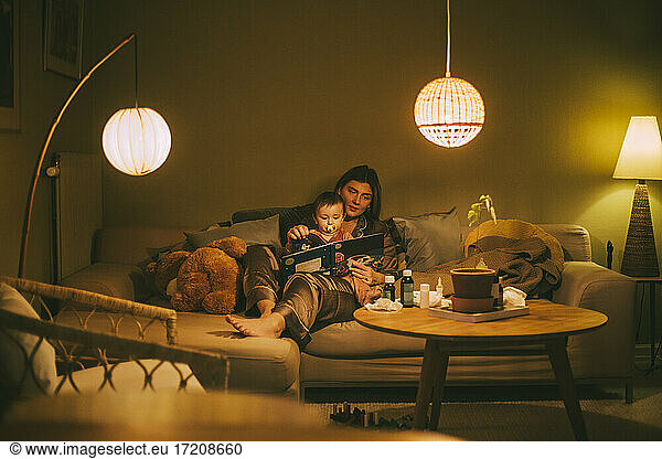 Mother with baby girl reading book in living room
