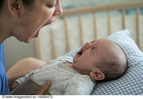 Mother with mouth open imitating yawning baby at home