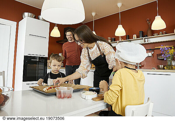 Mother with sons preparing pizza at home