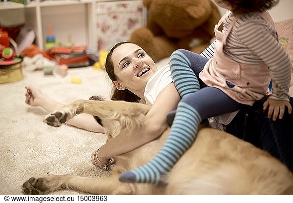 Mother with toddler and dog lying on the floor in child's room  in Munich  Germany.