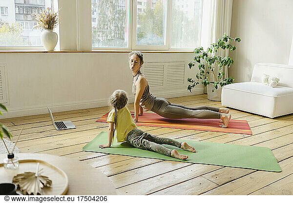 Mothering puckering at daughter exercising on mat