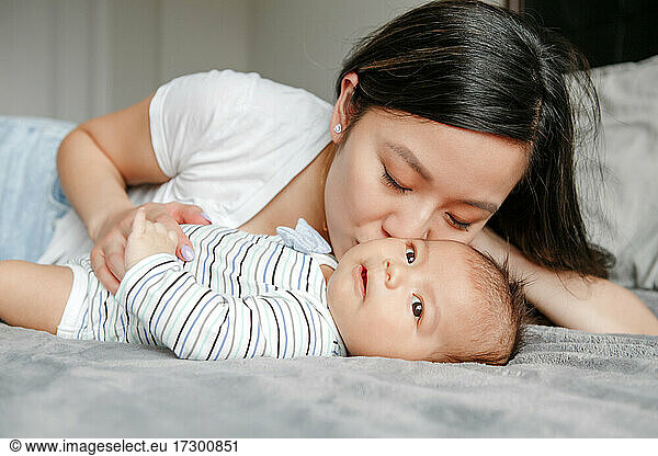 Mothers day holiday. Proud Asian mother hugging kissing newborn son.