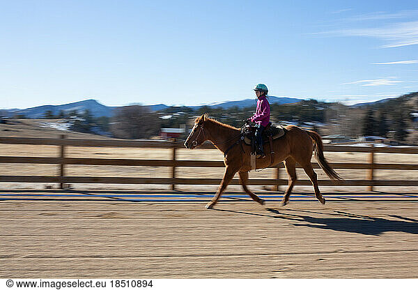 Motion blur of girl riding horse in arena