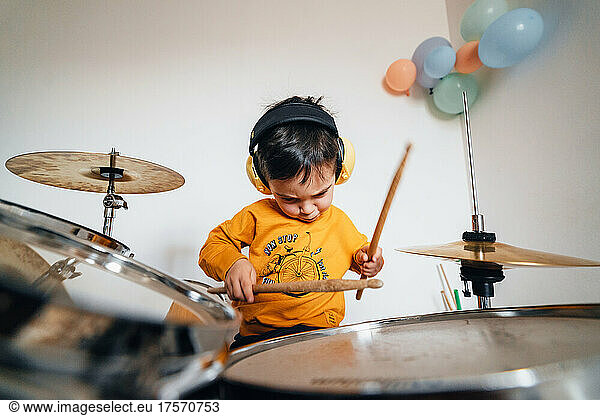 Motivated boy playing drums with sound isolation headphones
