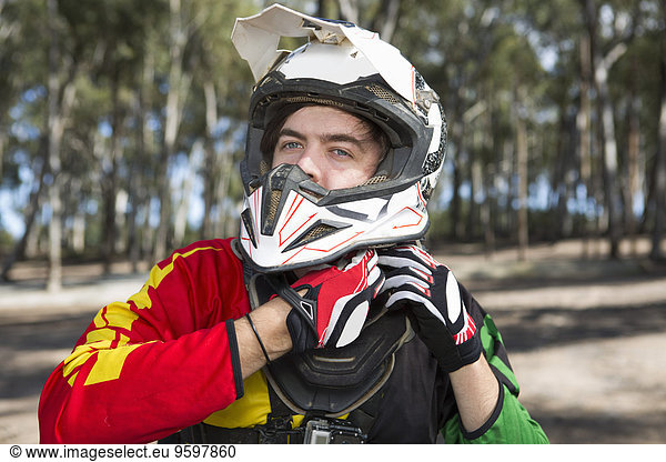 Motocross Motorrad-Wettbewerber Befestigung Helm im Wald