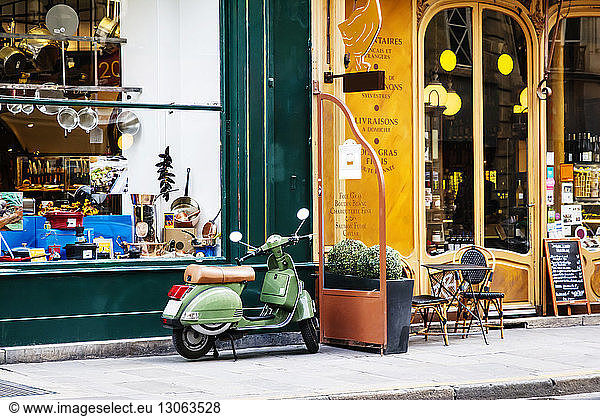 Motor scooter parked by shop