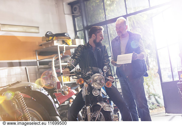 Motorcycle mechanic and customer talking in repair garage