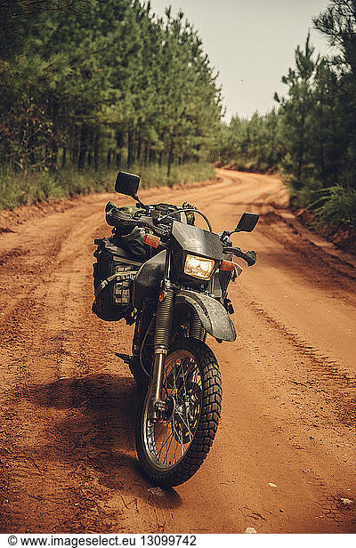 Motorcycle parked on dirt road by trees