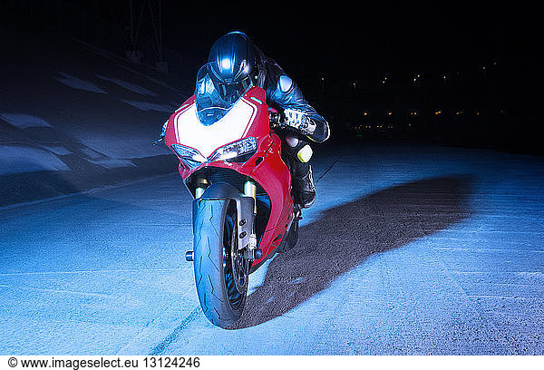 Motorradfahrer lehnt nachts auf Motorrad