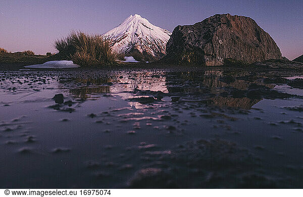Mount Taranaki volcano after the first snowfall of the season at sunset  New Zealand.