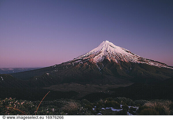 Mount Taranaki volcano after the first snowfall of the season at sunset  New Zealand.
