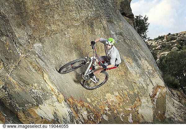 Mountain bike athlete does a wall ride on a trail in the mountains of Santa Barbara.