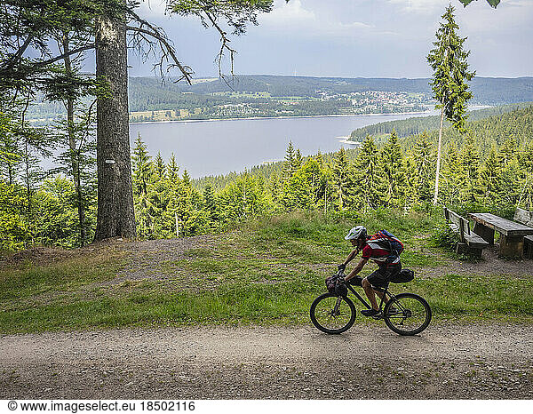Mountain biker cycling by lake in the background near Schluchsee  Baden-Württemberg  Germany