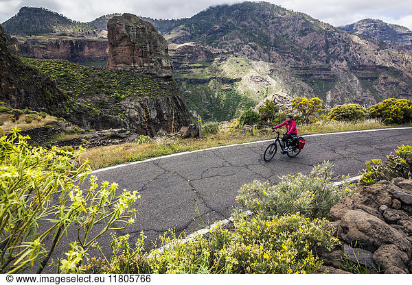Mountain biker riding electric bicycle on mountain road
