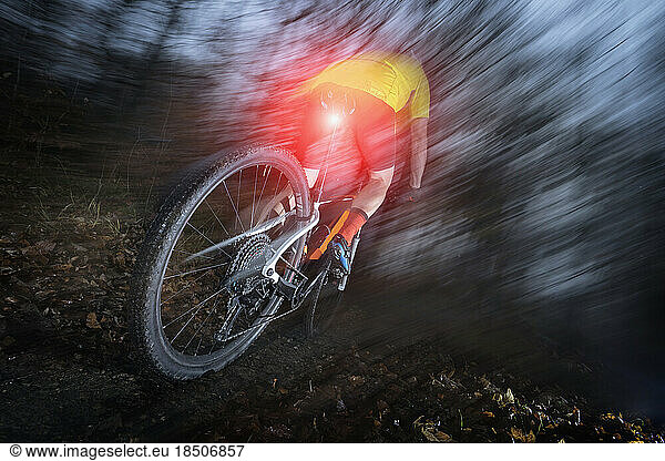 Mountain biker speeding at night on forest track  Bavaria  Germany