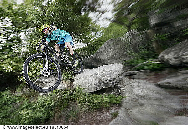 Mountain biker speeding through rocky forest path