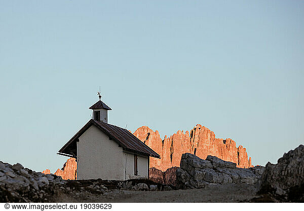 Mountain chapel with high rocky ridge on background at twilight. Tre Cime di Lavaredo National Park  Dolomites  Italy