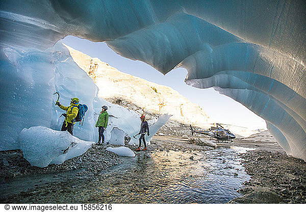 Mountain guide brings two female clients into ice cave to go climbing.