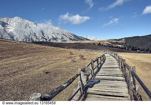 Mountain range and diminishing perspective of wooden walkway  Yak Meadow  Lijiang  Yunnan  China