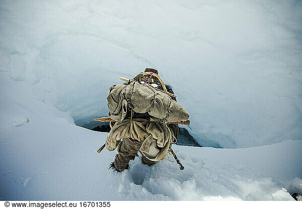 Mountaineer approaches a steep hole  access to ice cave.