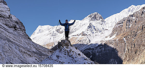 Mountaineer cheering on top of a rock  Dhaulagiri Circuit Trek  Himalaya  Nepal