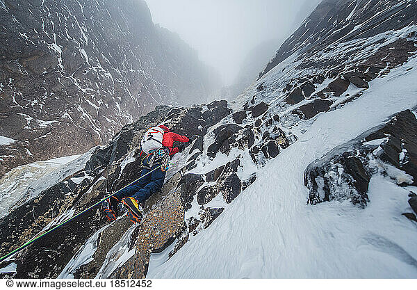 Mountaineer climbing rock and ice wall in snow