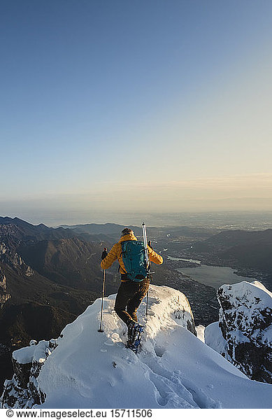 Mountaineer reaching the top of a snowy mountain enjoying the view  Lecco  Italy