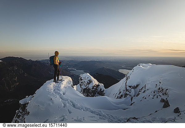 Mountaineer standing on top of a snowy mountain enjoying the view  Lecco  Italy