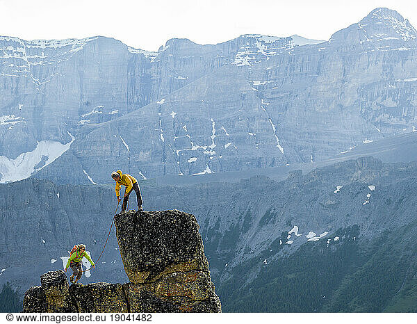 Mountaineering couple ascend rock pinnacle  mountains