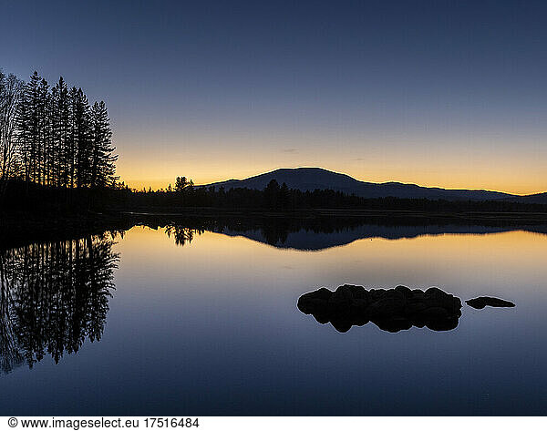 Mountains and trees reflected in mirror smooth flagstaff lake sunset