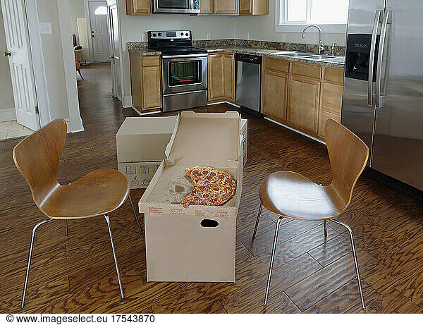 Moving house  relocation  cardboard boxes piled up in a kitchen  a pizza in a carton