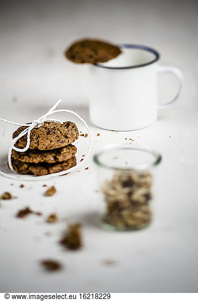 Mug with cookie on edge  stack of cookies with glass of walnuts  close up