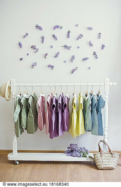 Multi colored dresses hanging on rack in front of wall with flowers