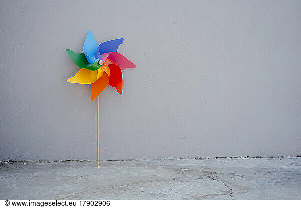Multi colored pinwheel toy in front of gray wall