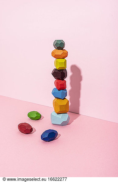 Multi colored wooden blocks stack against pink background