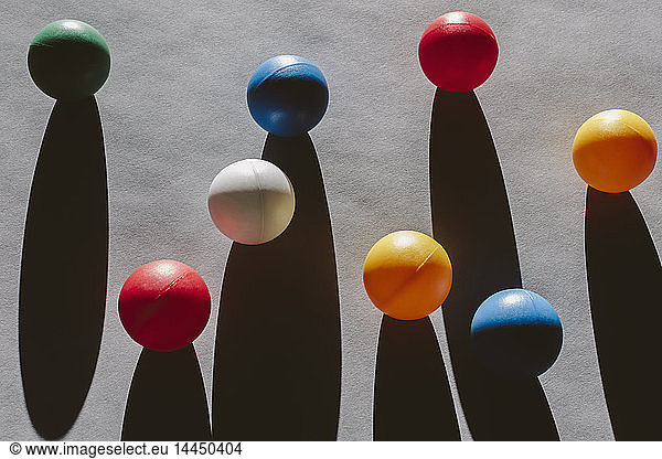 Multi-coloured balls arranged on wood background  casting long shadows