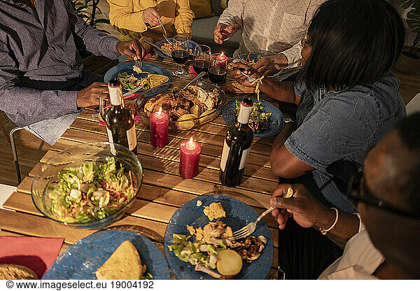 Multi-cultural senior friends having food and wine with candles on dining table