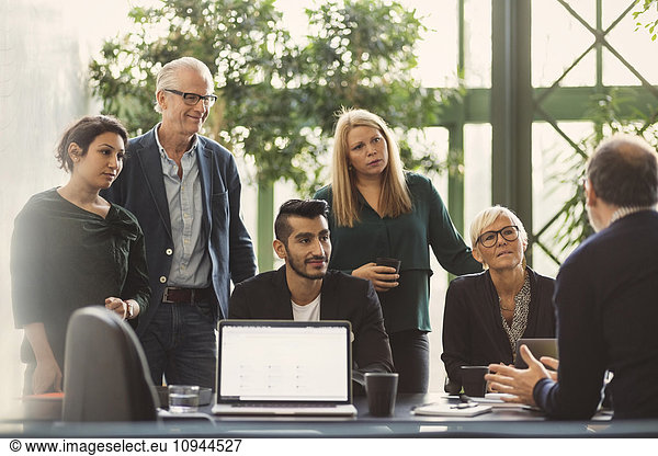 Multi-ethnic business people listening to manager in creative office