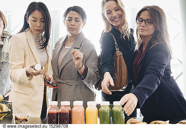 Multi-ethnic businesswomen looking at food and drink on table in event