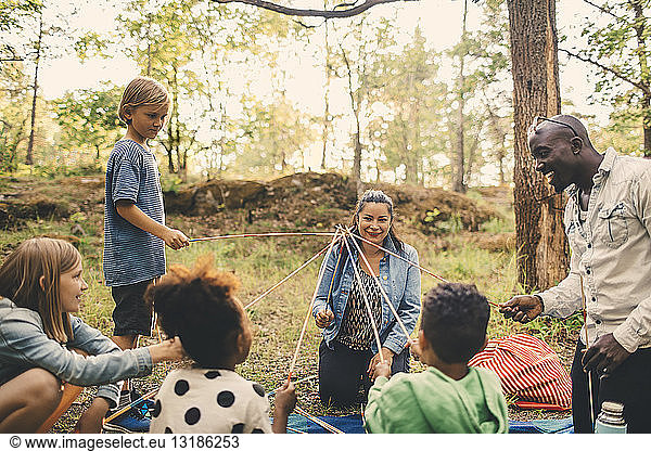 Multi-ethnic family playing with skewers at picnic spot in park