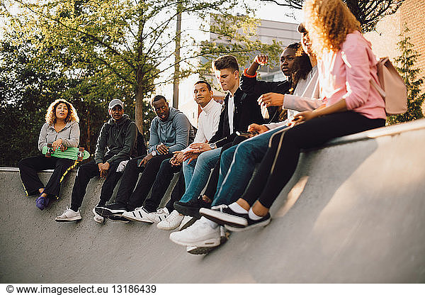 Multi-ethnic friends sitting at skateboard park