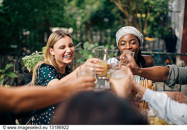 Multi-ethnic friends toasting drinks while sitting at balcony
