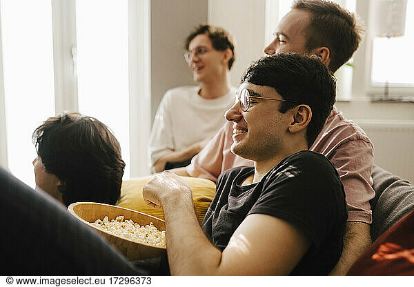 Multi-ethnic male friends having popcorn while watching sports in living room