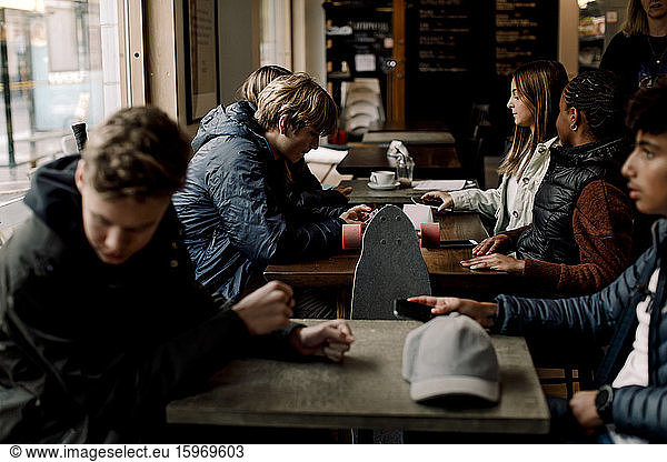 Multi-ethnic teenage friends sitting at table in cafe