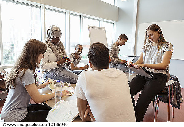 Multi-ethnic university friends discussing over project in classroom
