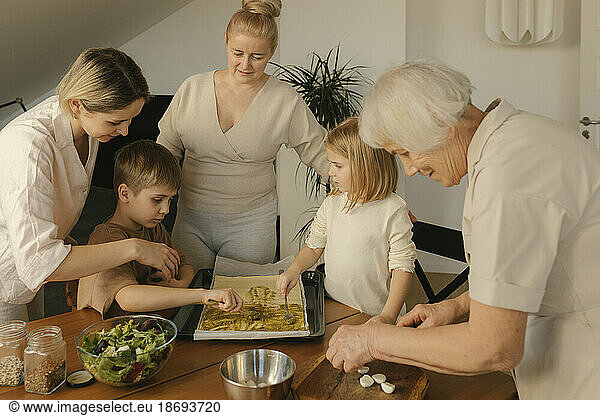 Multi-generation family assisting each other preparing food at home